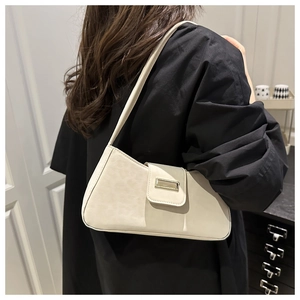 Gros plan du sac baguette crème avec boucle métallique et texture en cuir mat fine
