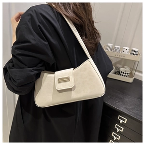 Detailansicht der cremeweißen Baguette-Tasche mit goldener Schnalle am Model
