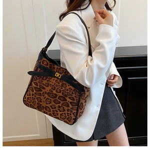 Detail of leopard print crossbody bag featuring gold metal turn-lock and black leather strap