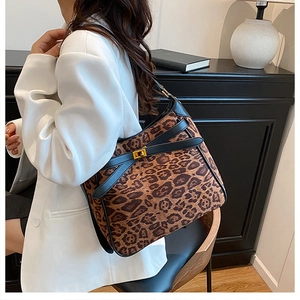 Detail of leopard print bucket bag with gold clasp and black leather straps on model