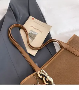 Detail der braunen Tragetasche aus Litschi-Leder mit geflochtenem Seil und Metallkette