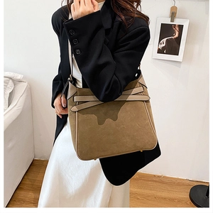 Brown suede crossbody bucket bag shown on model in a minimalist Nordic interior setting