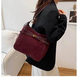 Detail showing high-quality burgundy suede texture and golden metal lock on saddle bag