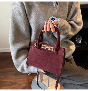 Detail view of burgundy frosted leather handbag with elegant gold metal lock clasp