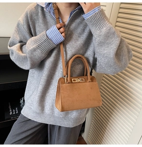 Brown frosted leather Kelly bag detail with metal turn-lock and adjustable shoulder strap