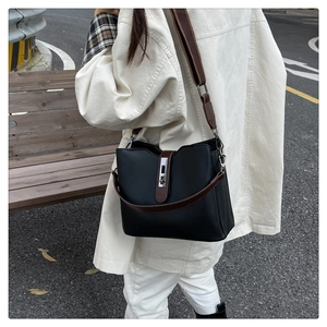 Detail view of the black leather bucket bag with brown strap and metal twist-lock