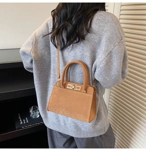 Vue arrière d'un sac à main en daim marron caramel porté à l'épaule avec fermoir doré