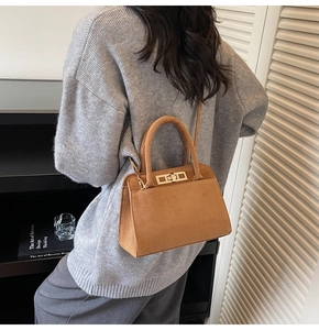 Vue arrière d'un mannequin portant le sac Kelly en daim marron en bandoulière stylée