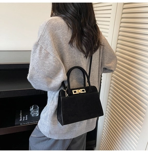 Détail d'un sac à main noir mat vintage porté à l'épaule avec une boucle dorée élégante