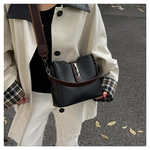 Detail of black leather bucket bag featuring contrast brown straps and silver swivel lock