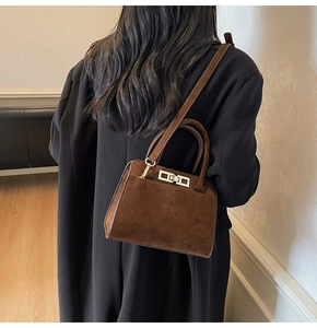 Détail du sac à main en daim marron mat avec fermoir doré et bandoulière amovible