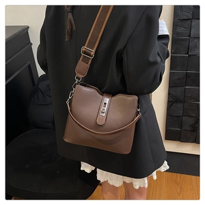 Close-up of vintage brown leather bucket bag with wide woven strap and silver twist lock