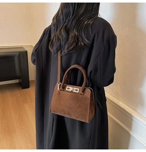 Détail du sac à main marron mat vintage porté par un mannequin dans un décor intérieur doux
