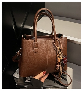 Close-up of brown litchi pattern leather tote with tassel and star leopard charms