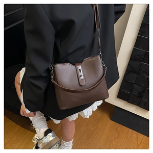 Detailed view of dark brown bucket bag with litchi texture and silver buckle
