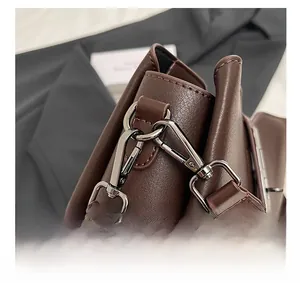 Macro detail of silver hardware buckle and pebble grain leather on brown bucket bag