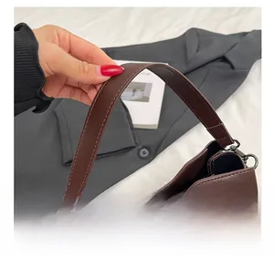 Detail showing comfortable hand strap and metal buckle of the brown bucket bag