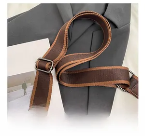 Detail of striped woven shoulder strap with adjustable silver buckle and leather connector
