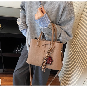 Close-up of brown litchi pattern leather tote with leopard bear charm and tassel