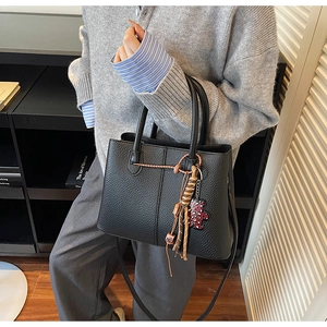 Detail of black pebbled leather tote with woven tassel and leopard print heart charm