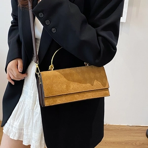 Brown faux suede crossbody bag with diamond quilting and gold handle held by a model