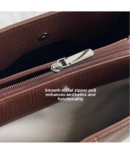 Detail of silver hardware zipper pull with herringbone fabric lining in leather bag