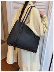 Modella indossa borsa tote in pelle martellata nera con piedini metallici protettivi