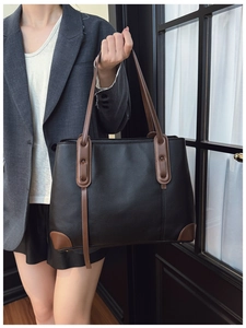 Modella che indossa una borsa tote nera con manici e angoli in pelle marrone