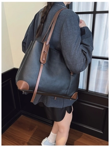 Dettaglio borsa tote in pelle martellata nera con tracolla marrone e ampio spazio