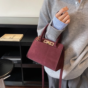 Sac à main vintage bordeaux en daim avec boucle dorée porté par un mannequin en maille