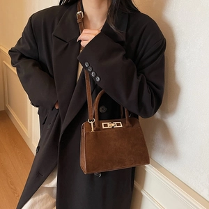 Sac Kelly vintage en cuir marron dépoli avec bandoulière sur un modèle en veste noire