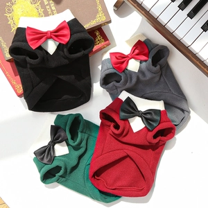Detail of multi-color pet tuxedo sweaters with bow ties on a vintage piano background