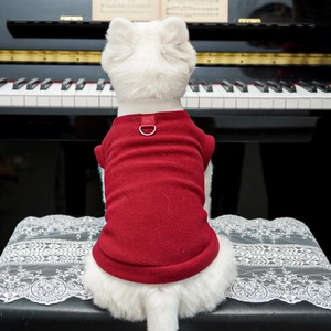 Dettaglio del gilet in pile rosso per cani con anello a D su un cane bianco al piano