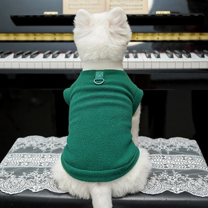 Dettaglio del gilet in pile verde per cani con gancio a D su sgabello da pianoforte