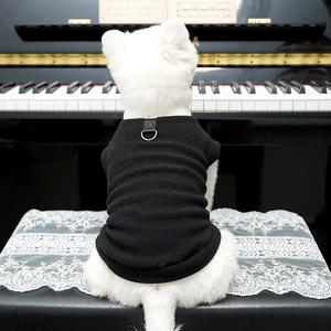 Dettaglio del gilet in pile nero per cani con anello a D su un cane vicino al piano