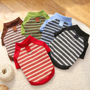 Close-up of five colorful striped pet sweaters with built-in D-rings on soft white rug