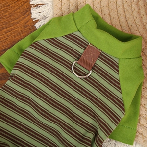 Detail of green striped pet shirt showing metal D-ring for leash attachment and fabric