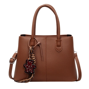 Brown litchi leather tote bag with dual handles and leopard bear charm on white background