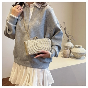 Dettaglio di una lussuosa pochette da sera con motivi di perle e catena dorata