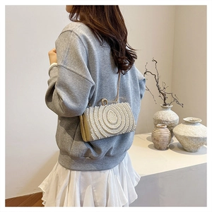 Dettaglio della pochette da sera con perle, catena dorata e chiusura in cristallo