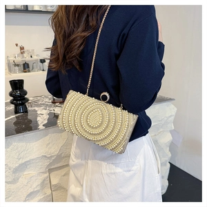 Dettaglio della pochette da sera con trama in perle e chiusura ad anello con diamanti