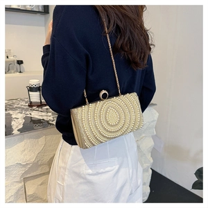 Dettaglio di borsa da sera con perle vintage e catena dorata su modella in blu