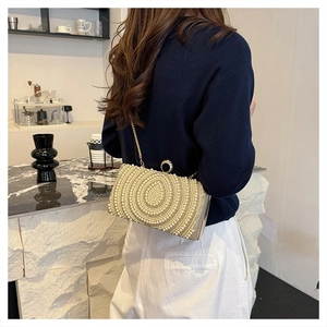 Dettaglio della pochette da sera con perle e tracolla a catena con chiusura ad anello