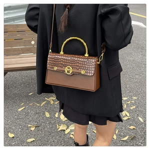 Detail of vintage PU leather box bag with bamboo handle and golden M-shaped magnetic buckle