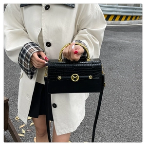 Detail of black crocodile texture PU leather handbag with golden bamboo handle and M logo
