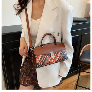 Detail of multi-color woven handbag featuring premium brown leather handle and silver metal clasp