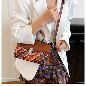 Detail of multi-color woven leather texture and silver metal twist lock on top-handle bag