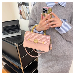 Detail of pink PU box bag with crocodile texture, gold M logo and metal ring handle