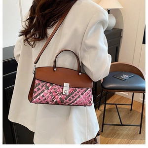 Detail of multi-color woven handbag with brown leather flap and silver buckle on model