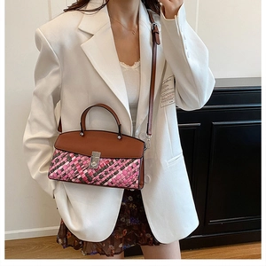 Detail of colorful woven kelly bag with silver lock worn with a white blazer